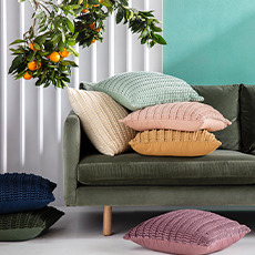 Textured velvet cushions stacked onto a green velvet sofa