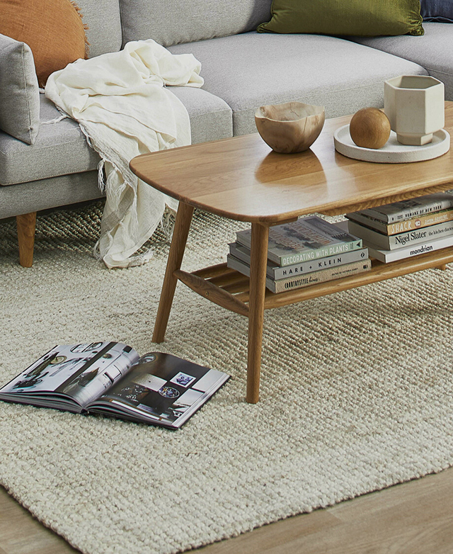 The relaxed jute rug looks aomfortably at home partially beneath a sofa, and underneath a book-filled coffee table.