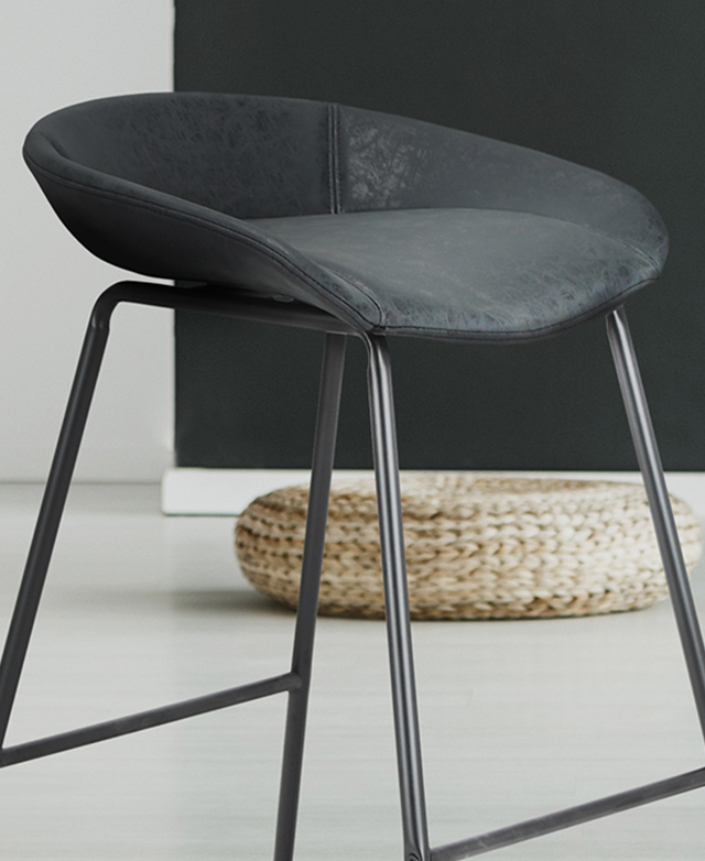Zooming in on the low-profile seat shows its faux leather upholstery, stitch accents, and subtle curving shape.