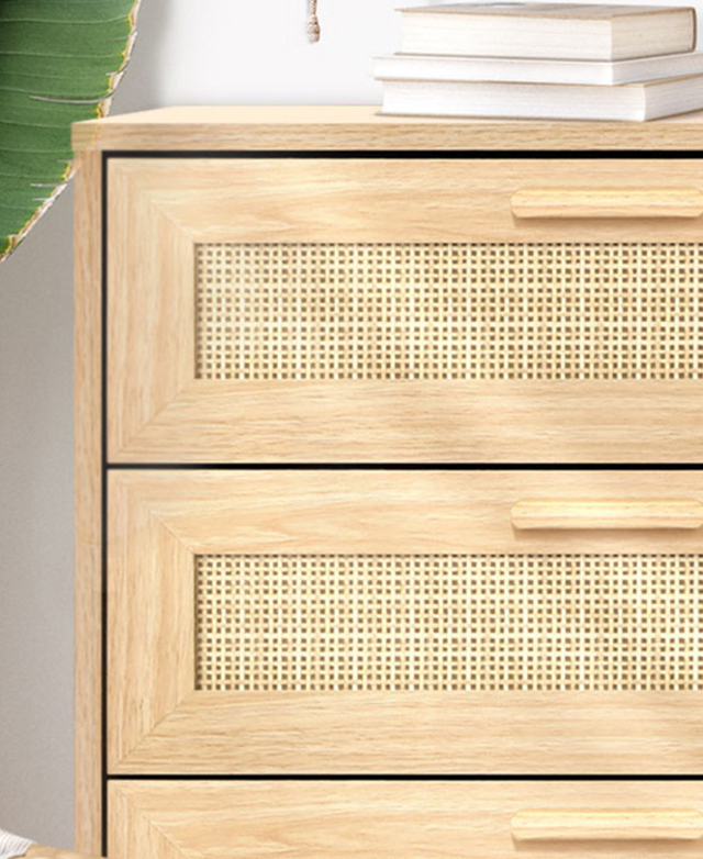 The cropped close-up of the chest features a small stack of books on top, and the rattan weave is shown in detail.