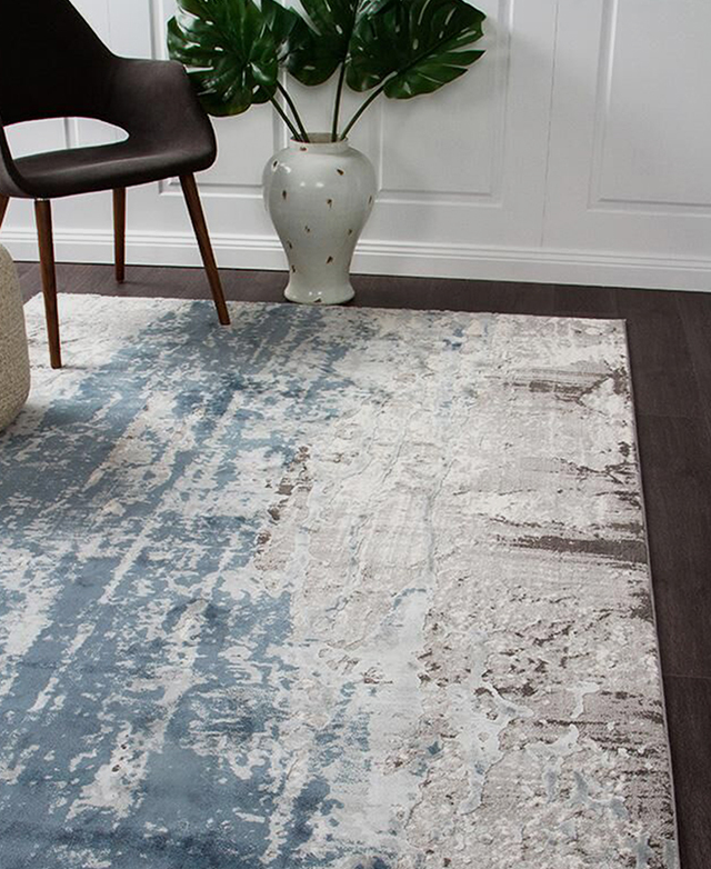 Styled on top of a dark timber floor, the rug's blue, cream, and brown print stands out.