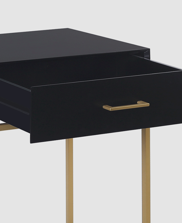 Close-up angle of a black table with one drawer pulled out. The drawer has a sleek horizontal bar handle in a gold finish.