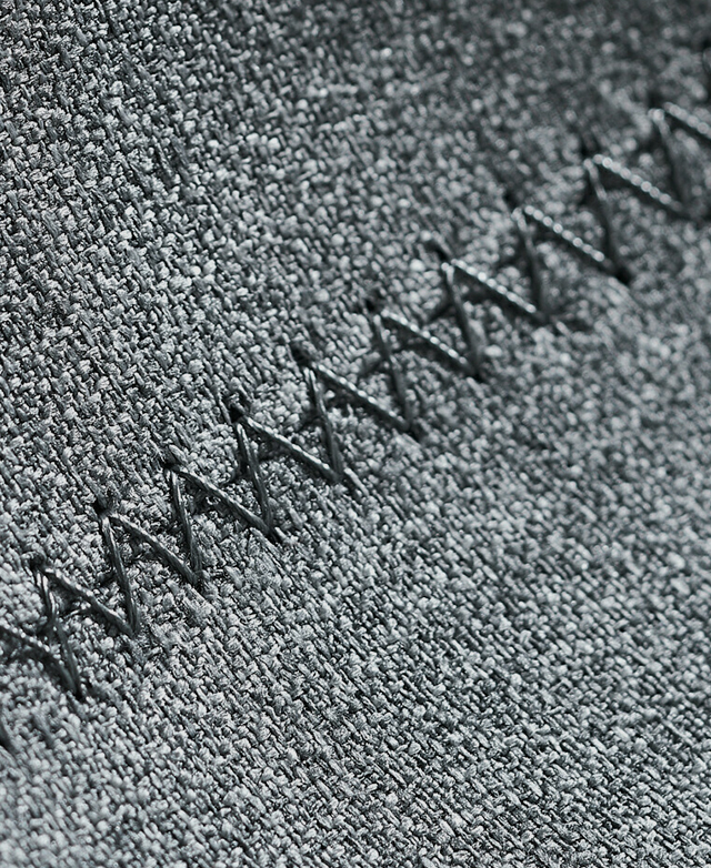 Extreme close-up of the decorative stitch detail that embellishes the grey polyester upholstery on the seat. Extreme close-up of the decorative stitch detail that embellishes the grey polyester upholstery on the seat.