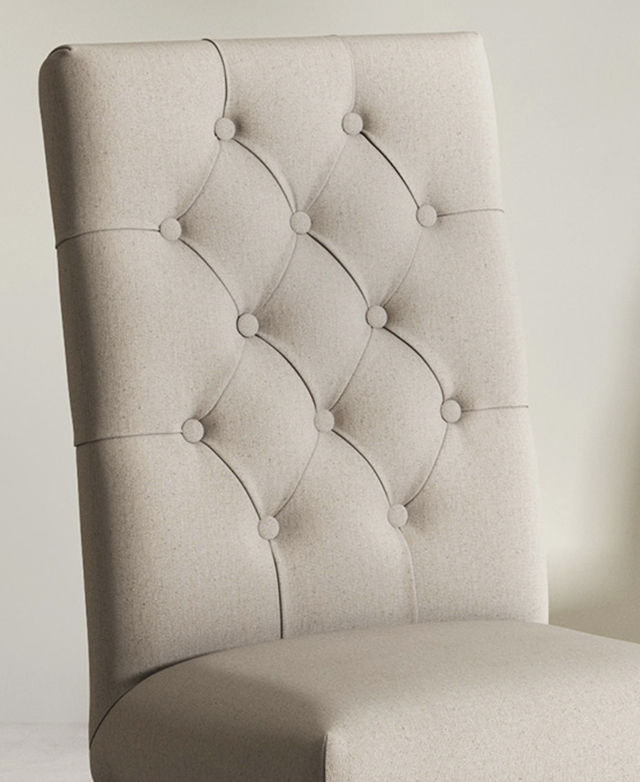 The seat of a chair upholstered in beige linen-cotton upholstery, with button tufting on the interior of the tall backrest. The seat of a chair upholstered in beige linen-cotton upholstery, with button tufting on the interior of the tall backrest.