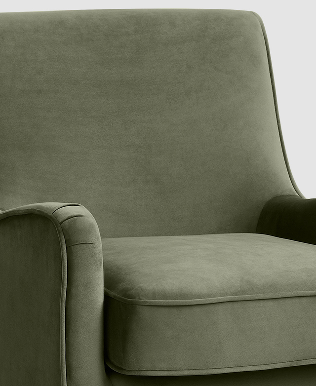 A mid-century modern chair with moss green velvet upholstery and thick piping trims around the seat edges and base cushion. A mid-century modern chair with moss green velvet upholstery and thick piping trims around the seat edges and base cushion.