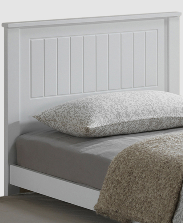 The headboard of a single size bed frame is in focus. It's white with etched panel details.