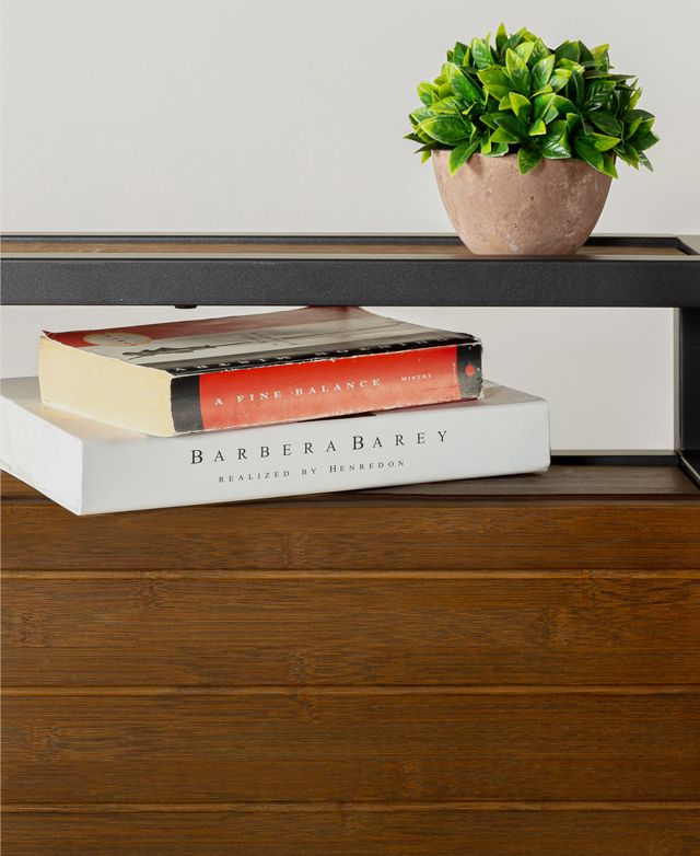 Two books are nestled in the shelf space that's built-in to the bedhead. A petite potted plant sits on the top.