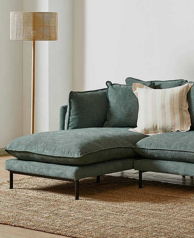 In a bright and neutral space, the chaise lounge connected to the right side of a blue-green sofa is shown. In a bright and neutral space, the chaise lounge connected to the right side of a blue-green sofa is shown.