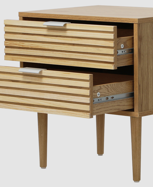 Two drawers on a timber bedside table are open, highlighting the metal runners on the side and arching shape of the lip pull handles at the top. Two drawers on a timber bedside table are open, highlighting the metal runners on the side and arching shape of the lip pull handles at the top.