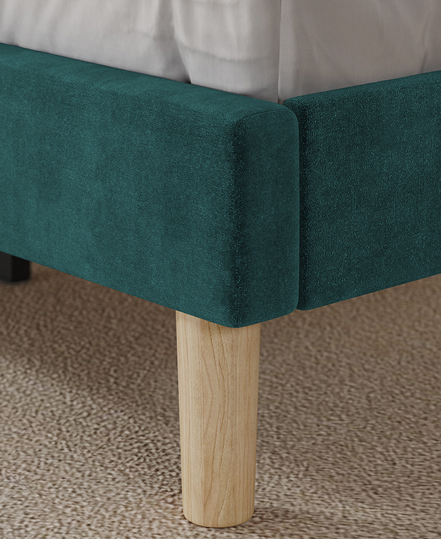 Large-scale view of a tapered rubberwood leg underneath the velvet bed frame.