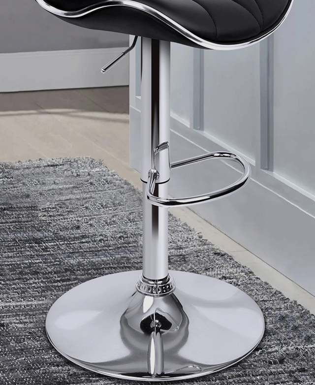 The chrome base of a swivel bar stool is in focus, with a semi-circle footrest built-in to the design. The chrome base of a swivel bar stool is in focus, with a semi-circle footrest built-in to the design.