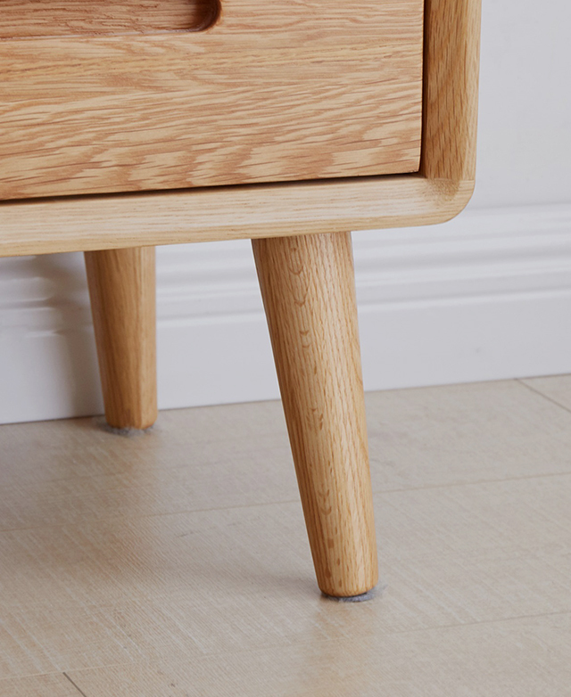 The natural oak legs of the wooden bedside table are tapered and splayed for style and stability.
