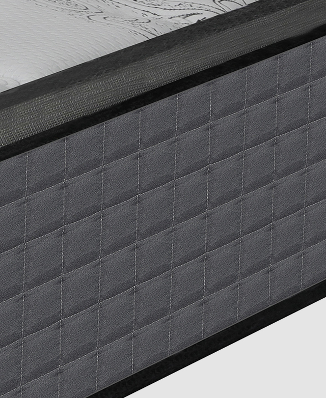 The side of a grey and white mattress with multiple layers and thick black piping trims.