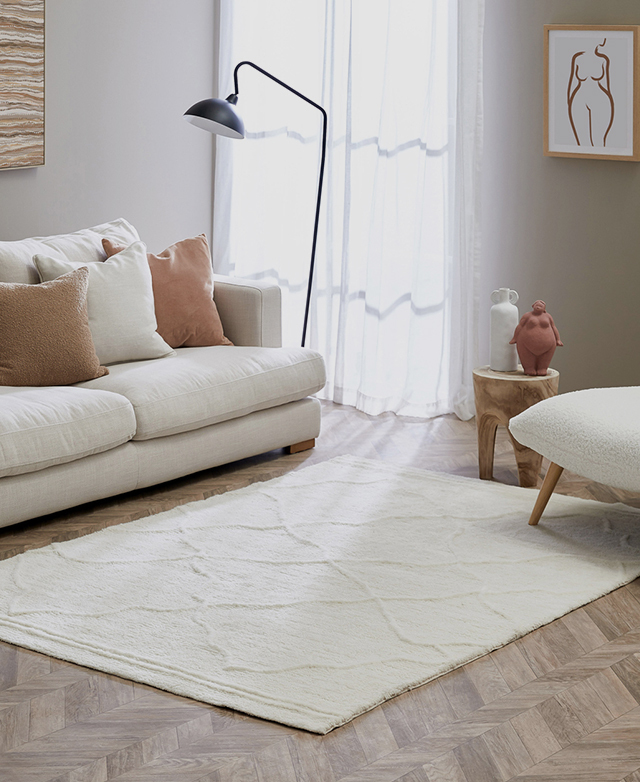 A white wool rug with a textured pile is styled above parquet timber flooring in a bright, contemporary living room. A white wool rug with a textured pile is styled above parquet timber flooring in a bright, contemporary living room.