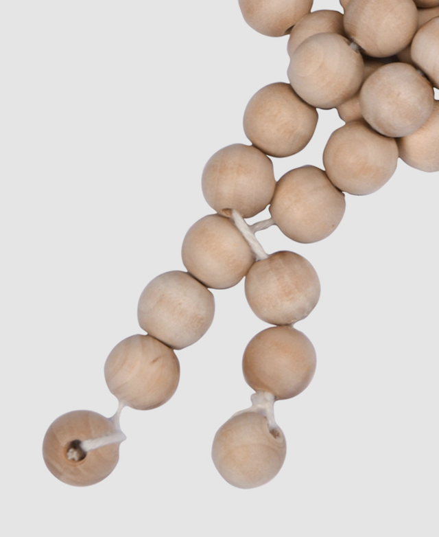 Round timber beads are connected by a white cotton string. Round timber beads are connected by a white cotton string.