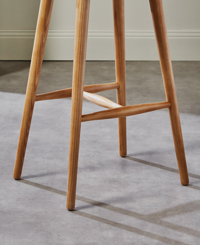 Tapered ash wood legs and strength-adding braces of a barstool. Tapered ash wood legs and strength-adding braces of a barstool.