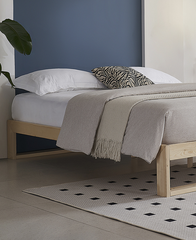 A timber bed frame with an elevated profile that leaves space for storage underneath,