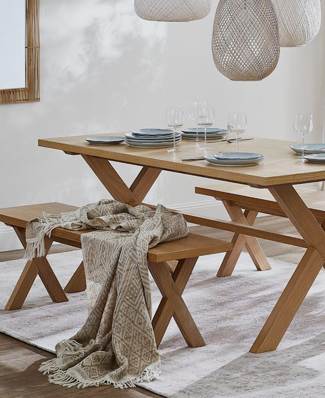 A timber dining table and matching timber bench seat are styled above a neutral area rug in a bright space. A timber dining table and matching timber bench seat are styled above a neutral area rug in a bright space.