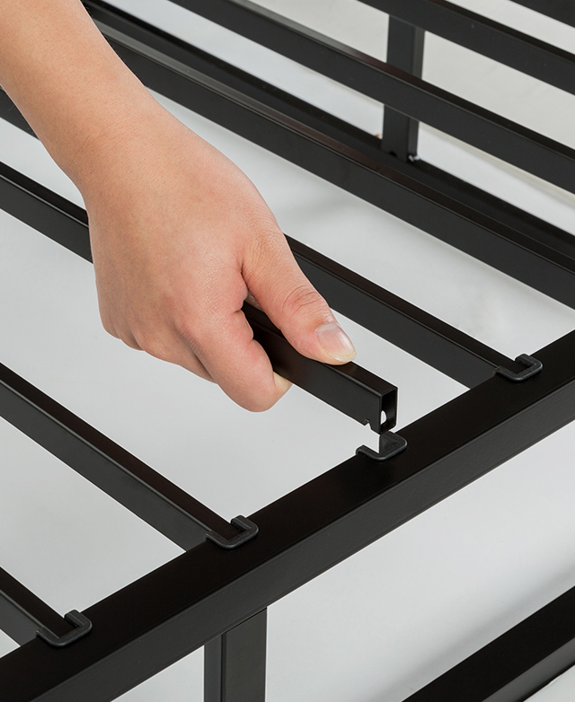 A hand is in the shot, assembling the metal slats along the interior of the bed base.
