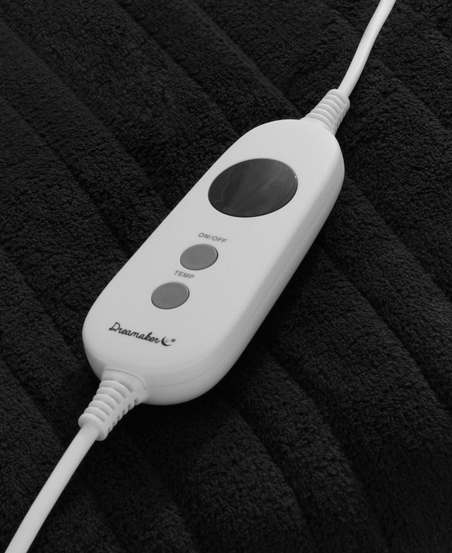 A fleece throw in a charcoal colour with a detachable remote controller is draped over the edge of a sofa. A fleece throw in a charcoal colour with a detachable remote controller is draped over the edge of a sofa.