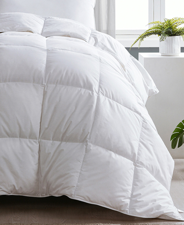 A quilt is draped over a bed, with the top edge folded down next to undressed pillows. A quilt is draped over a bed, with the top edge folded down next to undressed pillows.