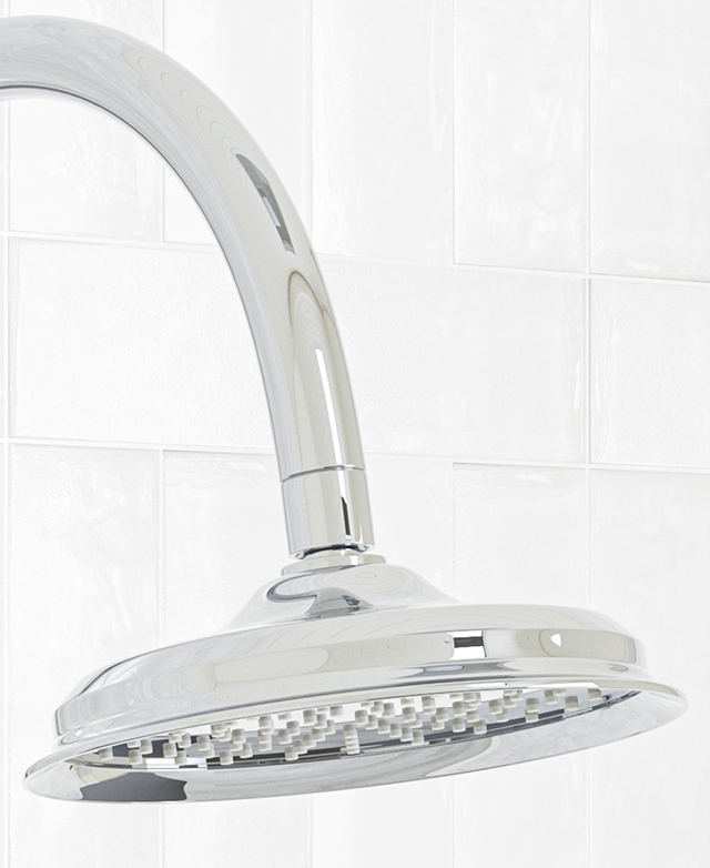 Top of the chrome Gooseneck Shower Arm & Head against a white tile wall