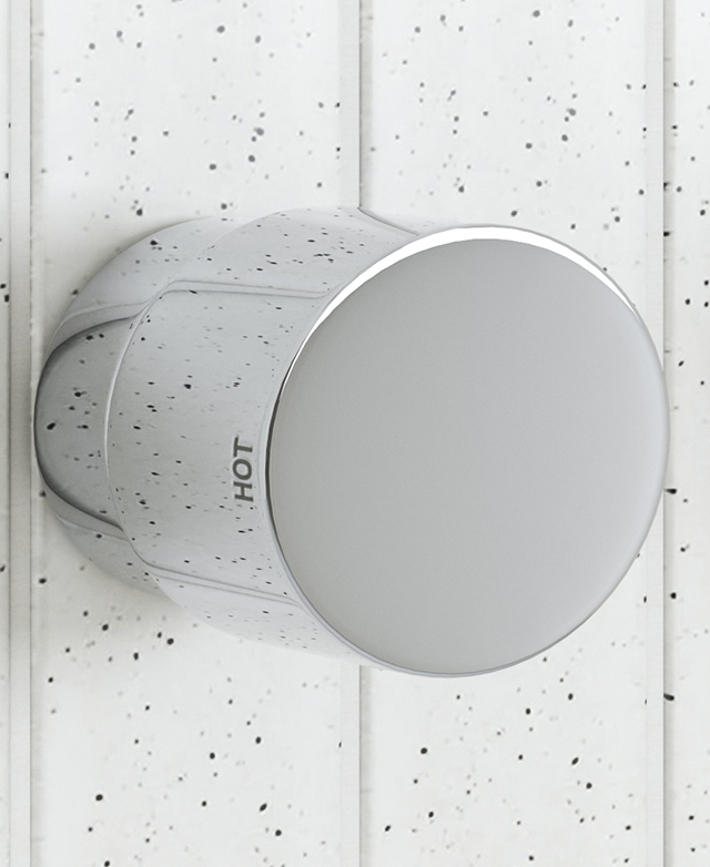 wall mounted chrome dial style tapware showing the hot indicator on the dial with a speckled tile background wall mounted chrome dial style tapware showing the hot indicator on the dial with a speckled tile background