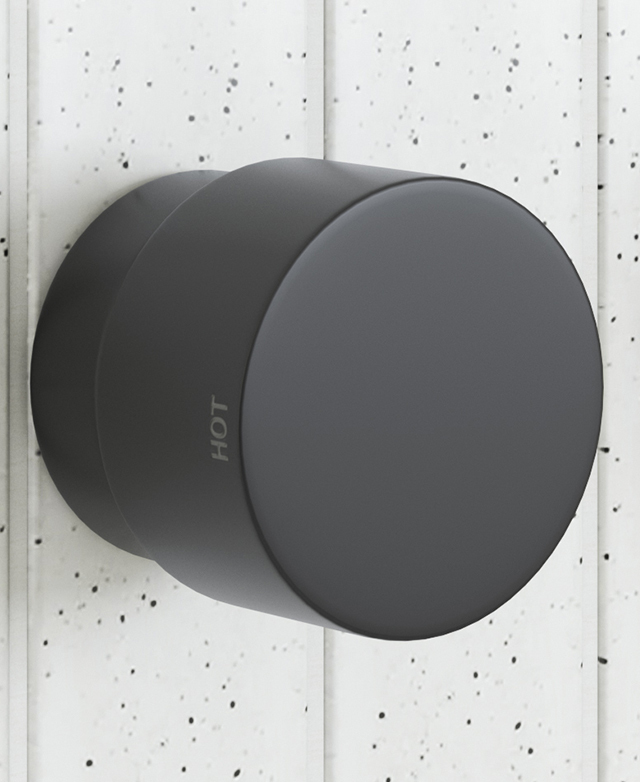 wall mounted matte black dial style tapware showing the hot indicator on the dial with a speckled tile background