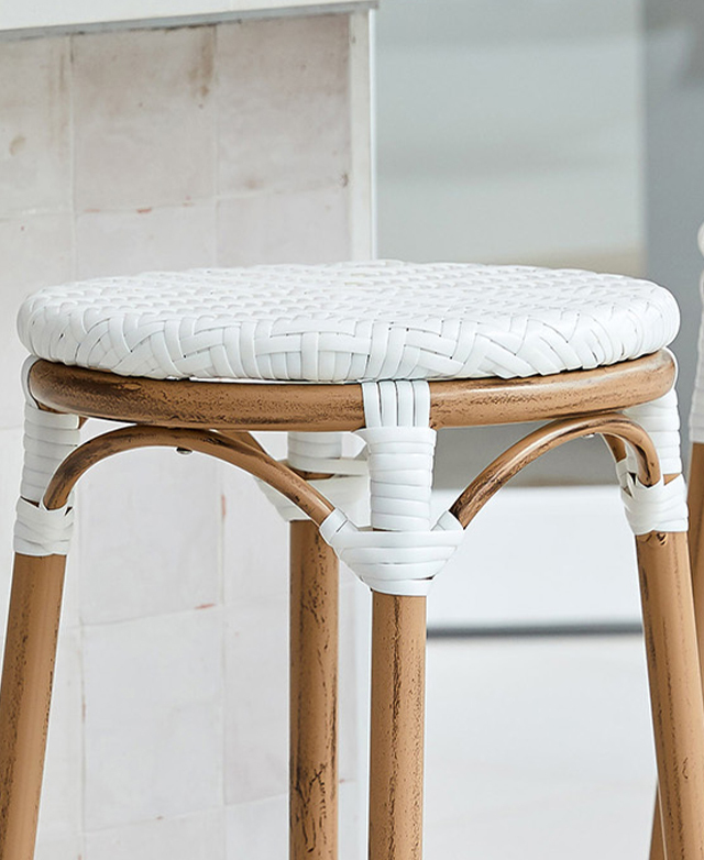 The barstool's white woven seat is shown near a tiled counter