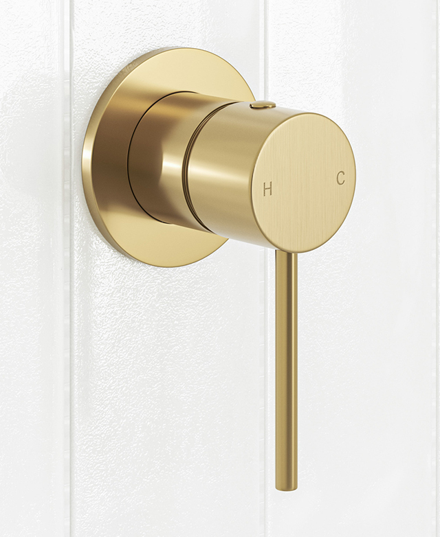 Brushed gold shower/bath wall mixer with pin lever mounted on a white tiled wall