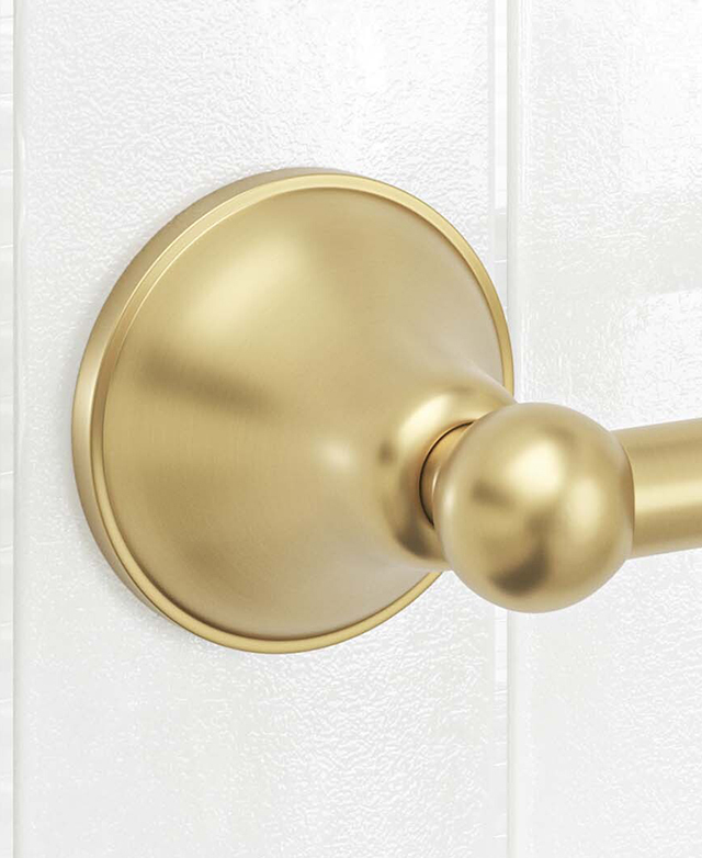 Close-up of brushed gold round toilet roll holder base and connection to holder against a white tiled wall