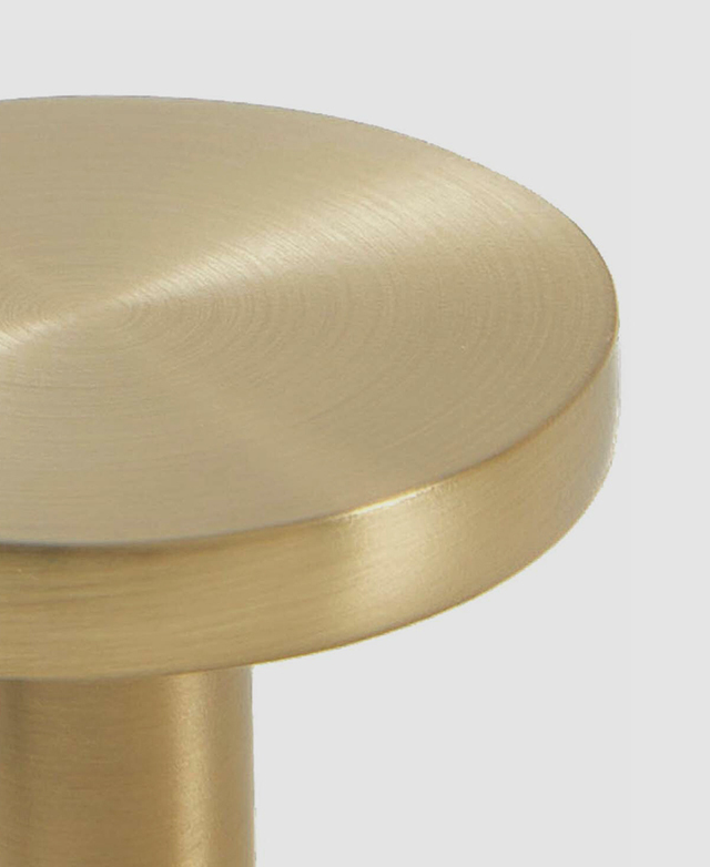 Part close-up of the brushed gold round front knob against a white background