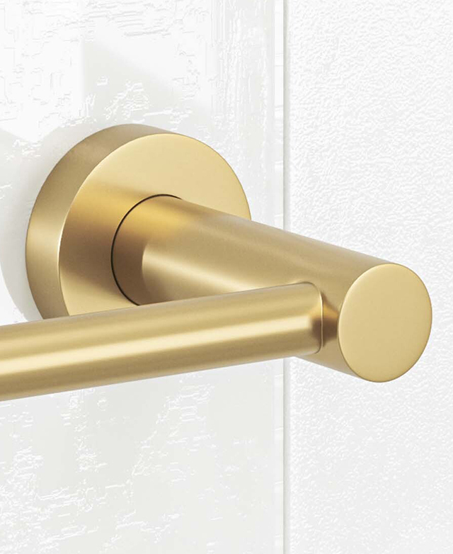 Close-up of the brushed gold round backplate and base with a part of holder before a white tiled wall