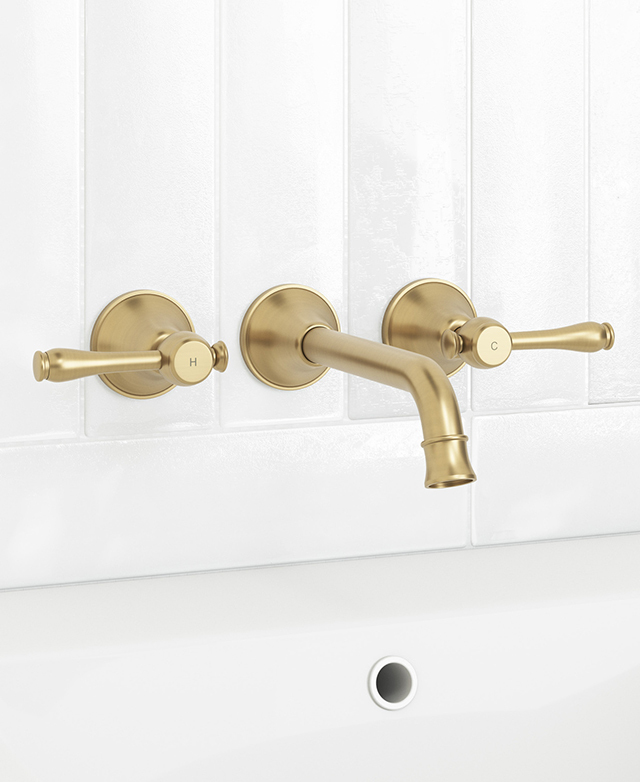 Stanwell brushed gold wall mixer mounted on a white tiled wall above part of basin