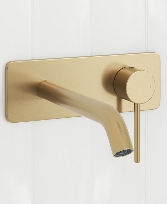 Clovelly brushed gold wall mixer set mounted on a white tiled wall