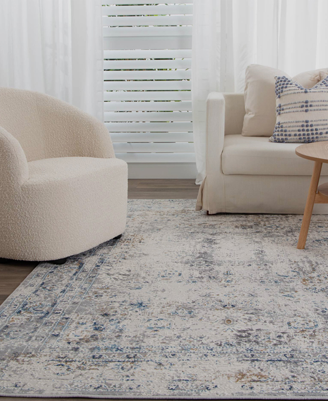 Grey tones, with a fabric ottoman and armchair on top of the rug, create a cool-toned setting. Grey tones, with a fabric ottoman and armchair on top of the rug, create a cool-toned setting.