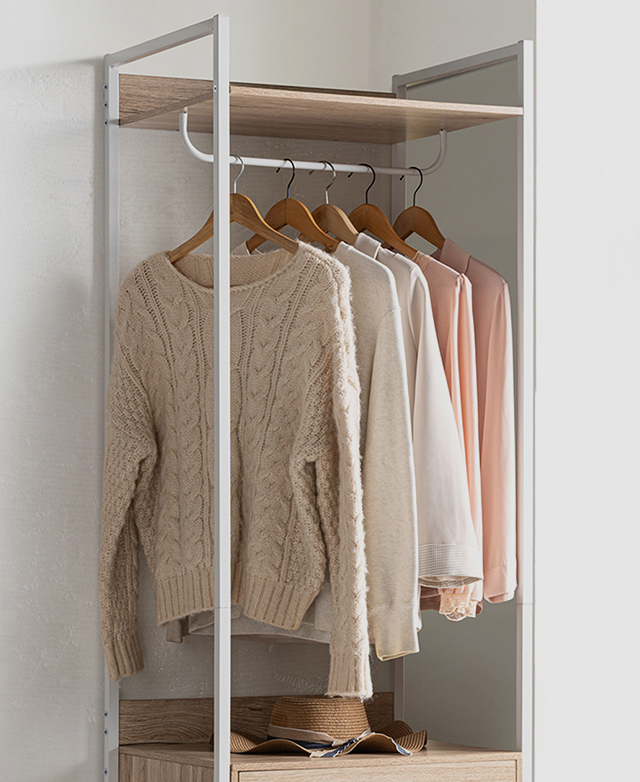 The top half of the white-framed wardrobe has clothes on the hanging rack and a hat on the shelf. The top half of the white-framed wardrobe has clothes on the hanging rack and a hat on the shelf.