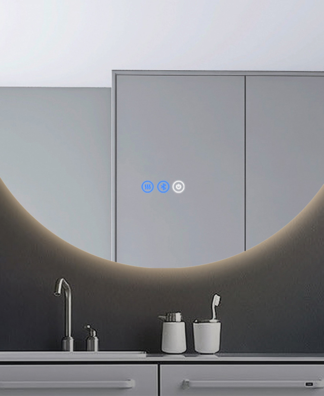 The bottom edge of the illuminated round mirror is fixed over a vanity.