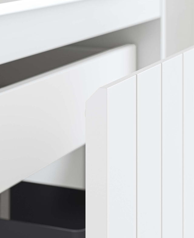 The bevelled top of the drawer is in focus, along with the smart vertical lines of the panelled drawer front in soft grey.