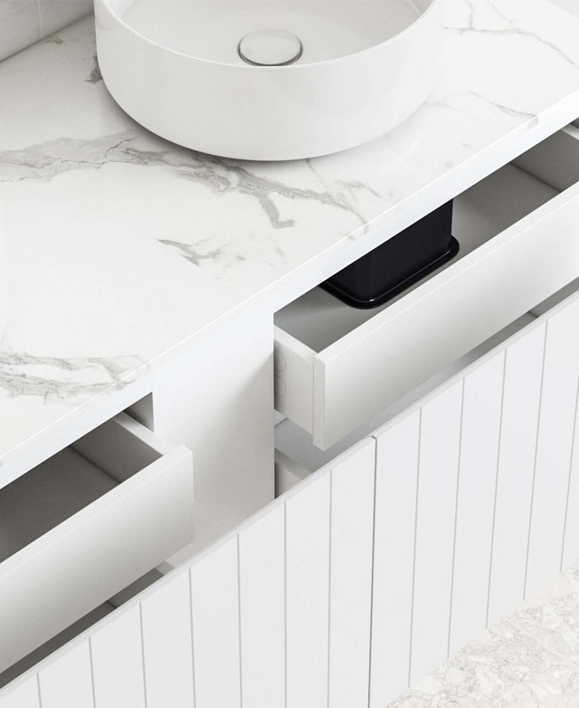 A high three-quarter view displays the clean lines, inner drawers pulled open, and the soft grey veining of the stone top.