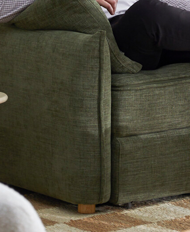 A cropped, close-up view of the green sofa bed indicates the sharp tailored and piped trims.