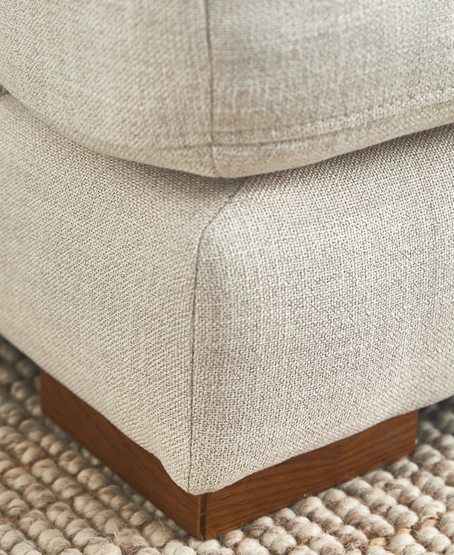 A corner of the sofa's base is supported by a short, square red oak foot.