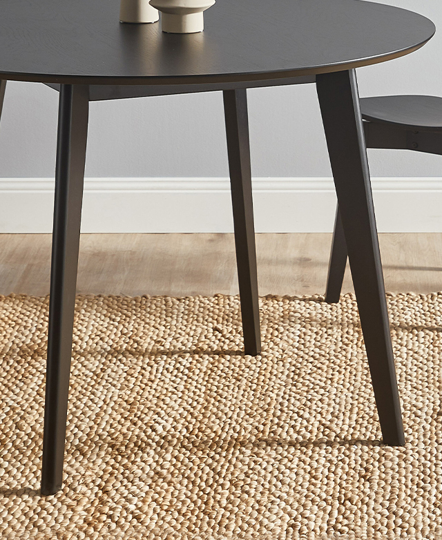 At eye level, the table's smooth, tapered rubberwood legs are in focus.