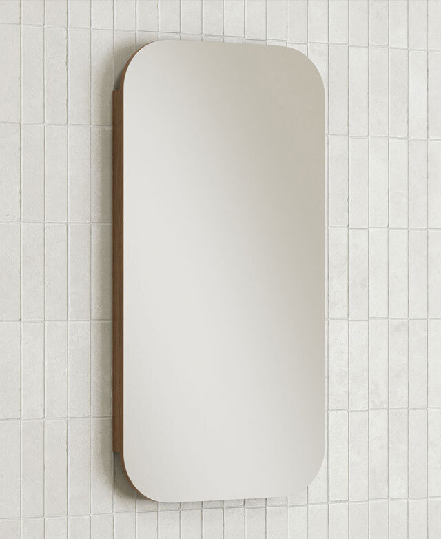 The rectangular mirror is mounted on a white tiled wall above a round white sink.