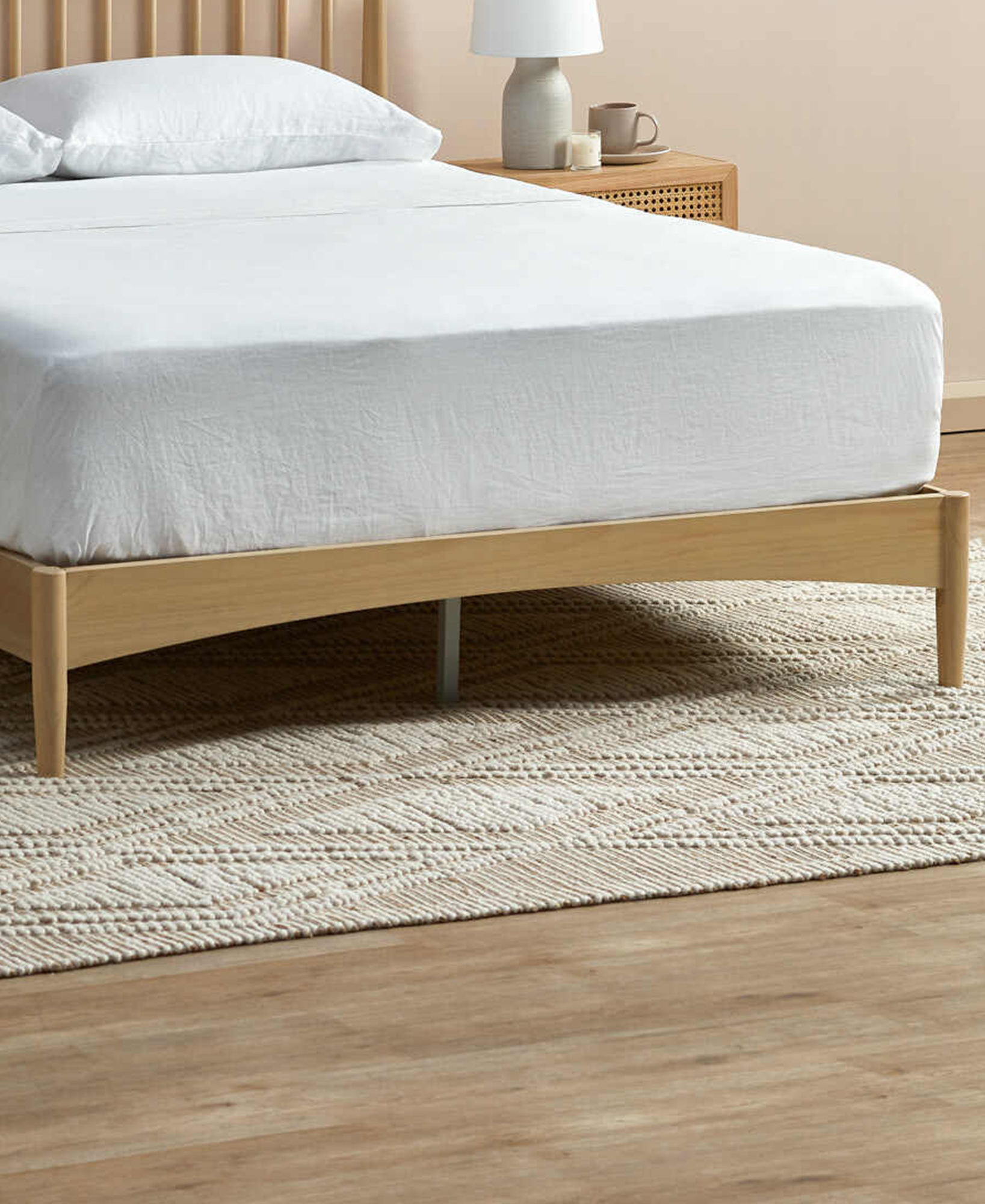 Front view of the bed with one cylindrical wooden leg and a central metal support leg on display.