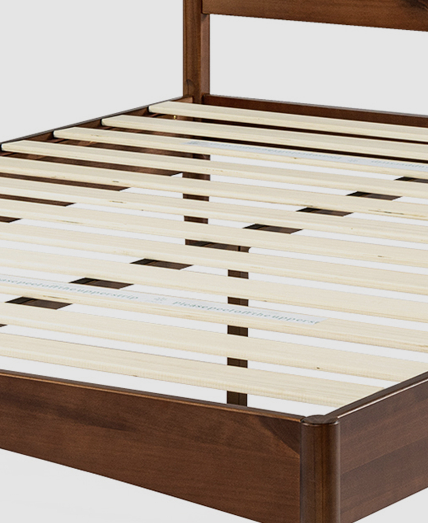 Walnut-coloured bed frame and plywood slats are displayed at an angle, close up.