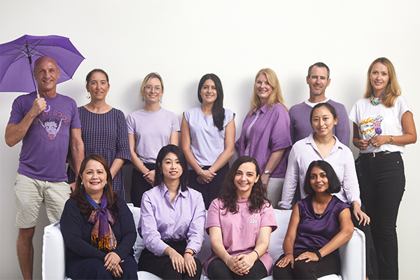 Members of the Temple and Webster team all dressed in purple posing for a photo on and behind a sofa for International Womens Day