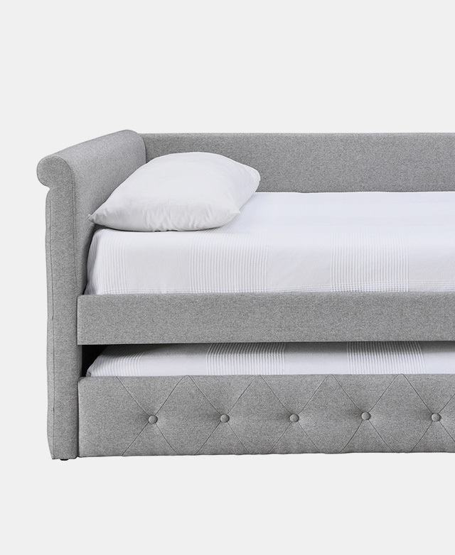 From the front, a cropped half-view of a grey sofa bed with trundle. From the front, a cropped half-view of a grey sofa bed with trundle.