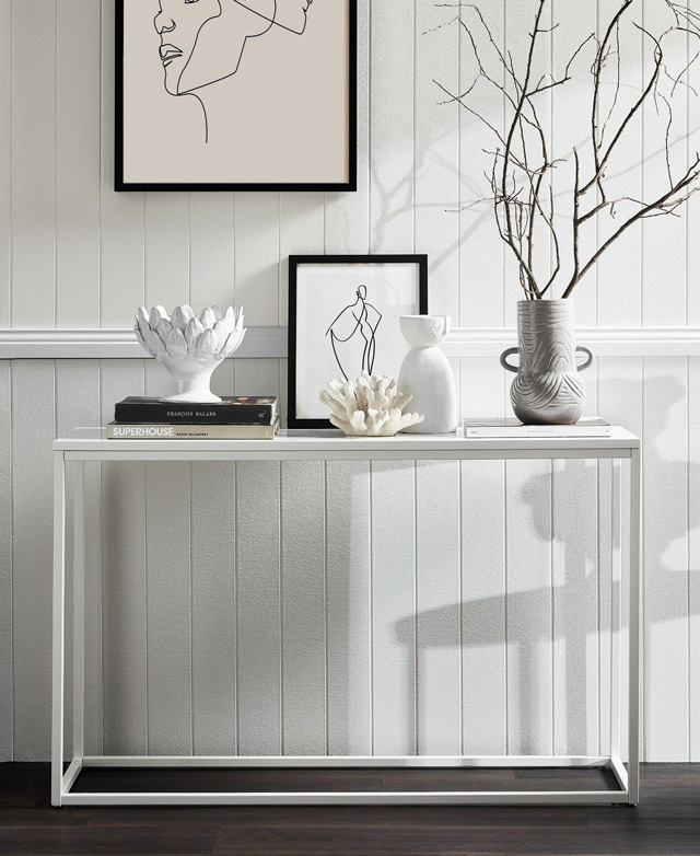 A crisp white setting with white decor and black accents, including a stack of books, branches, and white faux coral.