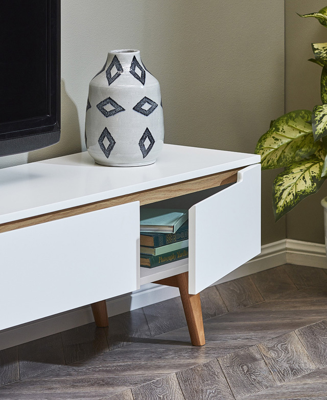 A three-quarter angle of the TV unit is cropped, showing one of the cupboard doors open, with books inside.